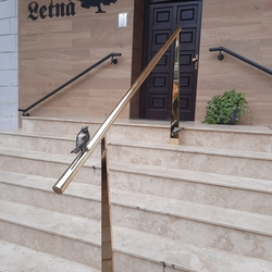 Brass handrail on the stairs at the entrance to the restaurant - a modern railing with a bird Brass handrail on the stairs at the entrance to the restaurant - a modern railing with a bird