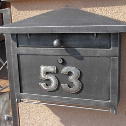 A wrought iron post box with a number sign A wrought iron post box with a number sign